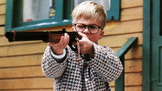 Ralphie from A Christmas Story holding up a Red Ryder BB Gun and aiming down its sight.
