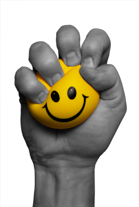 Photo of a black and white hand squeezing a yellow smiley face stress ball