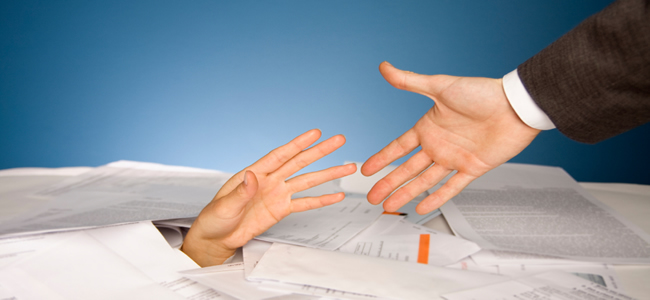 Business Man's hand reaching to grab hand reaching out of pile of papers