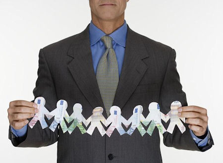 Photo of a businessman holding a stretched out linked cut-out of paper dolls, representing employee retention.