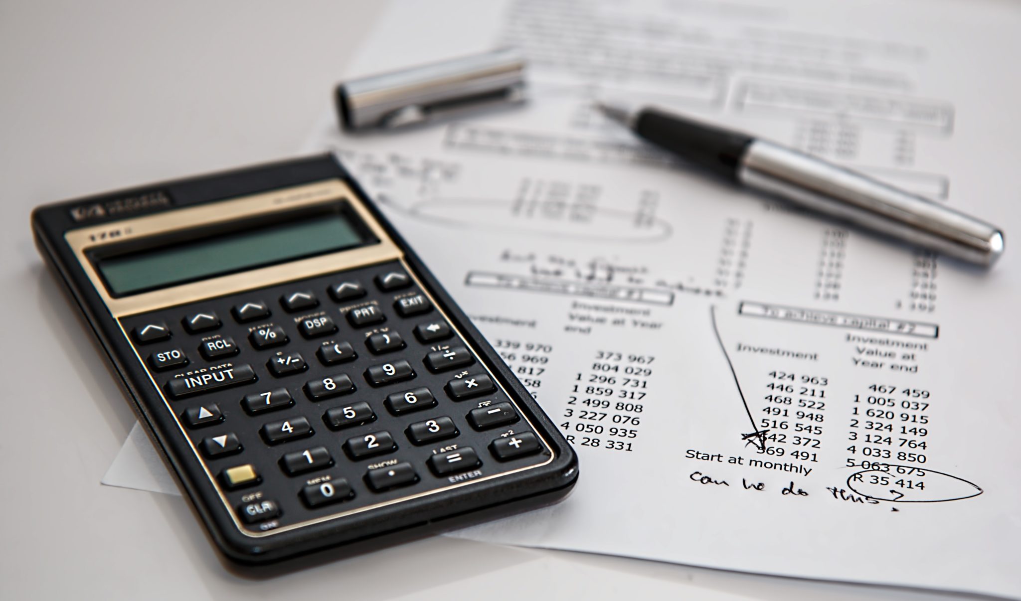 Photo of a calculator on top of financial documents, balancing totals.