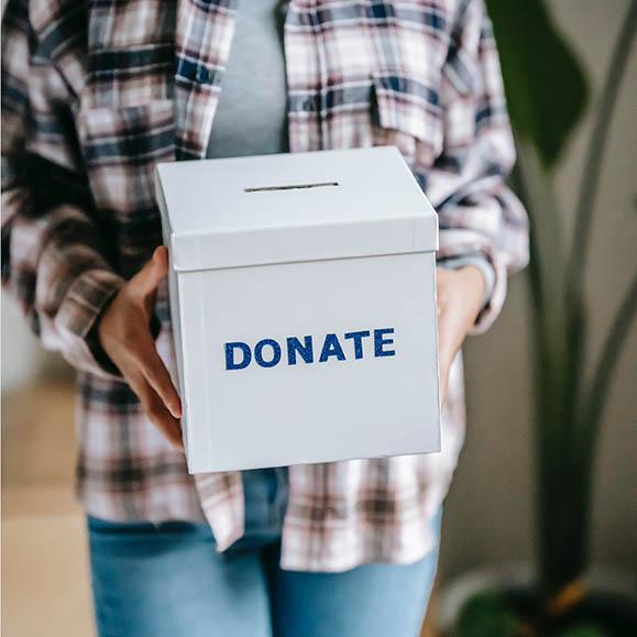 Person holding a box with a slot at the top with text on the front that says Donate